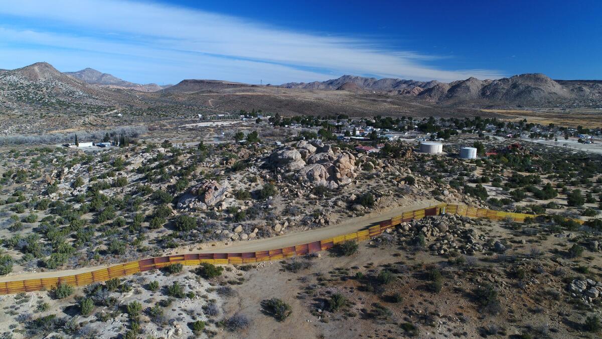 A drone view of the rusty ribbon of border fence that separates the Mexico town of Jacume and Jacumba Hot Springs, seen in background.