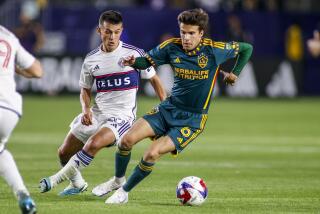 LA Galaxy midfielder Riqui Puig, right, controls the ball away from Vancouver Whitecaps.