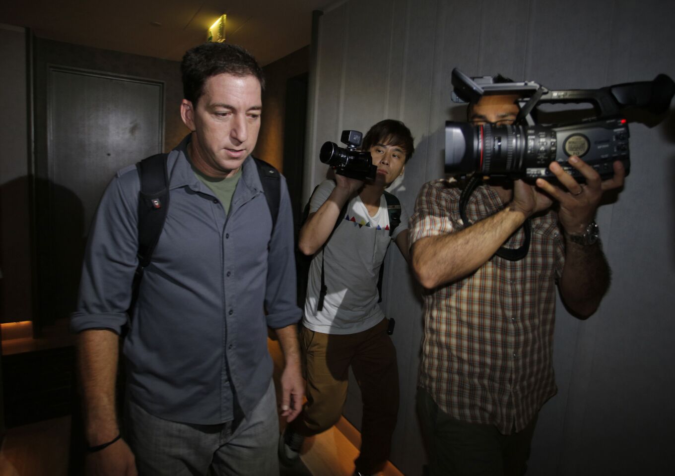 Glenn Greenwald, left, one of the reporters who broken the Edward Snowden leaks, walks out from his hotel room in Hong Kong.