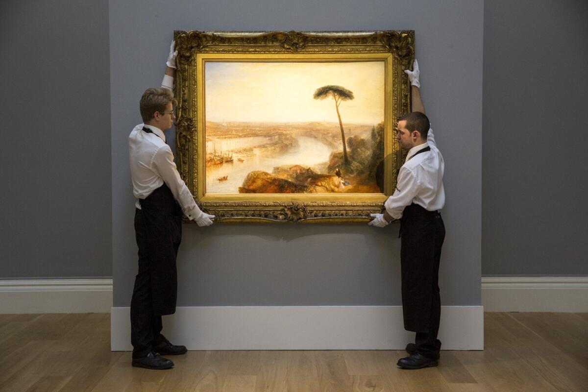 Gallery technicians at Sotheby's adjust the painting "Rome, from Mount Aventine," by J.M.W. Turner, on Nov. 28 in London.