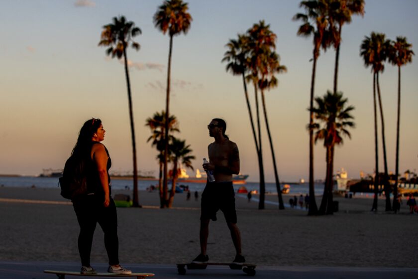 Long Beach, CA - August 28: Skateboarders take a sunset cruise along a cooler ocean's edge amid a hot summer day at Alamitos Beach in Long Beach, Sunday, Aug. 28, 2022. A heat wave is forecasted to take affect in Southern California this week. (Allen J. Schaben / Los Angeles Times)