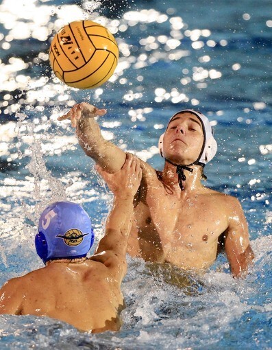 Huntington Beach High's James Vlachonassios, top, passes the ball inside to a teammate pressured by Corona del Mar's Charlie Rodosky (5) during the second half in a first round CIF Southern Section Division 1 playoff game in Newport Beach on Wednesday.