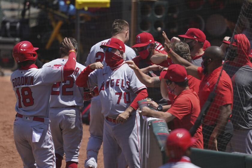 Los Angeles Angels manager Joe Maddon, center, greets players after a three-run home run by Mike Trout.