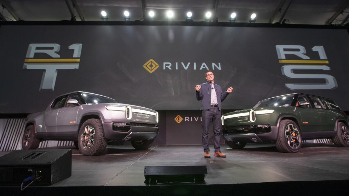 R.J. Scaringe, founder and CEO of Rivian, talks during the world premiere of the R1S electric SUV, right, and R1T electric truck, left, at the L.A. Auto Show at the Los Angeles Convention Center in November.