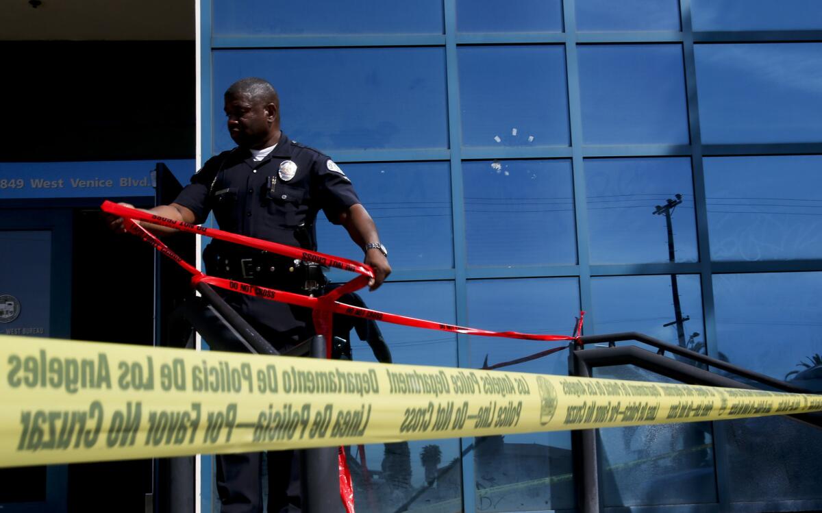 An LAPD officer attaches red tape to the railings at the entrance of the West Traffic Bureau at 4849 Venice Blvd. after a shooting in April.