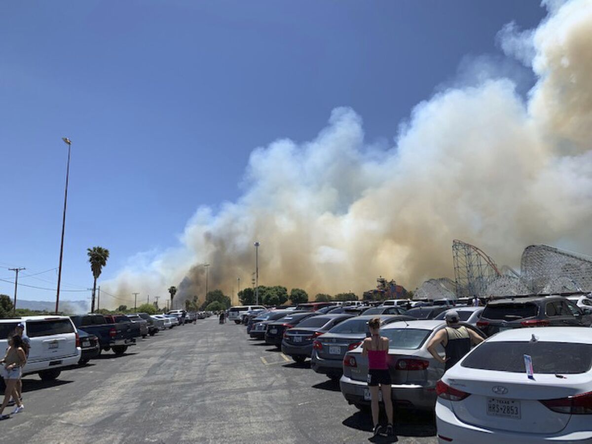 Heavy smoke from a fast-moving brush fire surrounds Six Flags Magic Mountain.