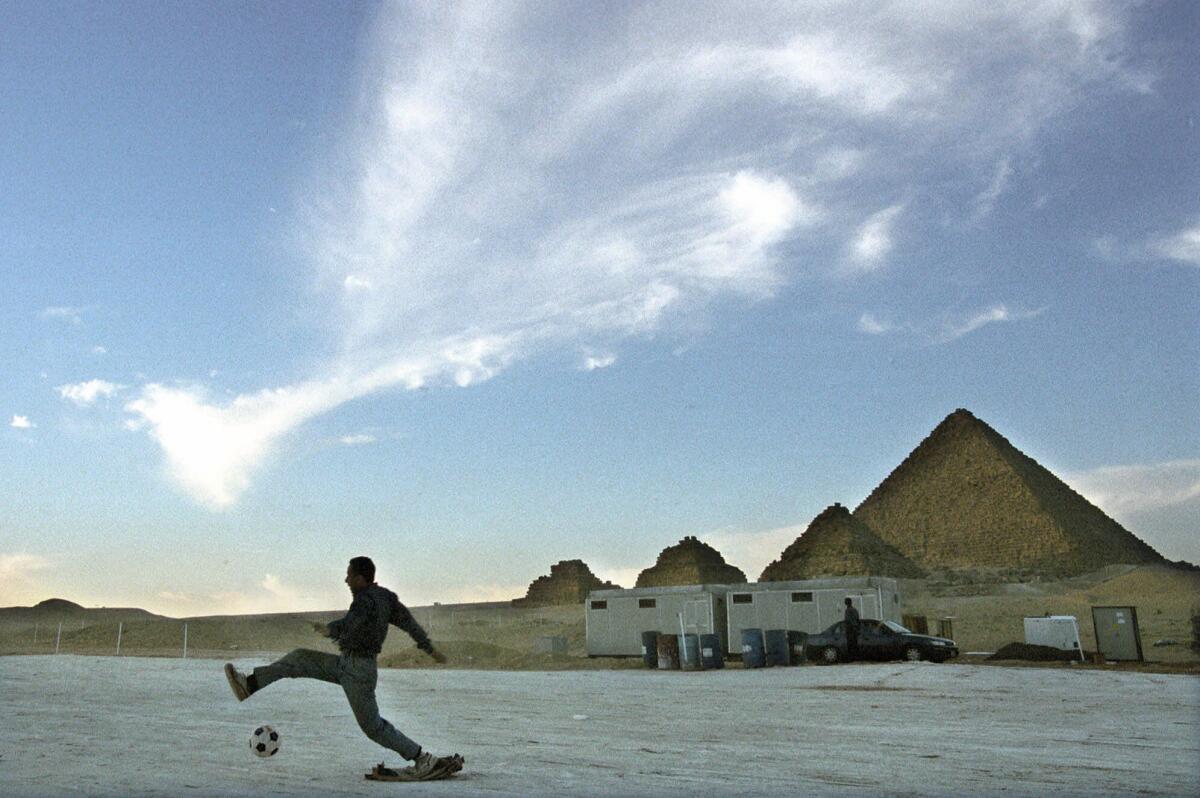 In this file photo from 1999, an Egyptian plays soccer next to the Giza pyramids.