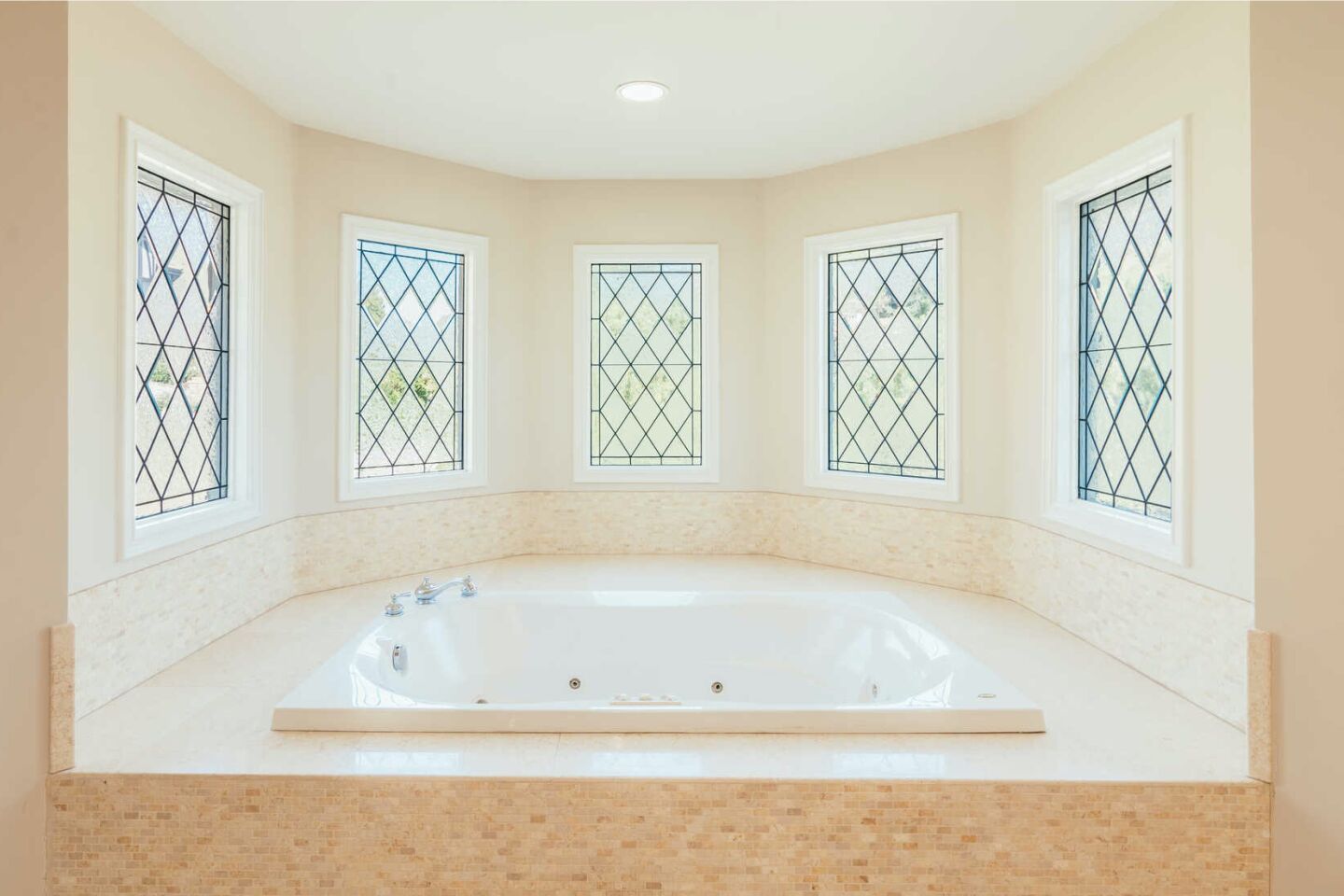 Mullioned windows in an alcove holding a spa tub.