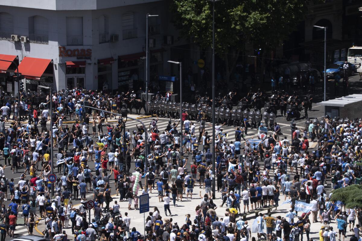 A view from above shows police lined up, blocking a Buenos Aires street in the face of a  a milling crowd. 