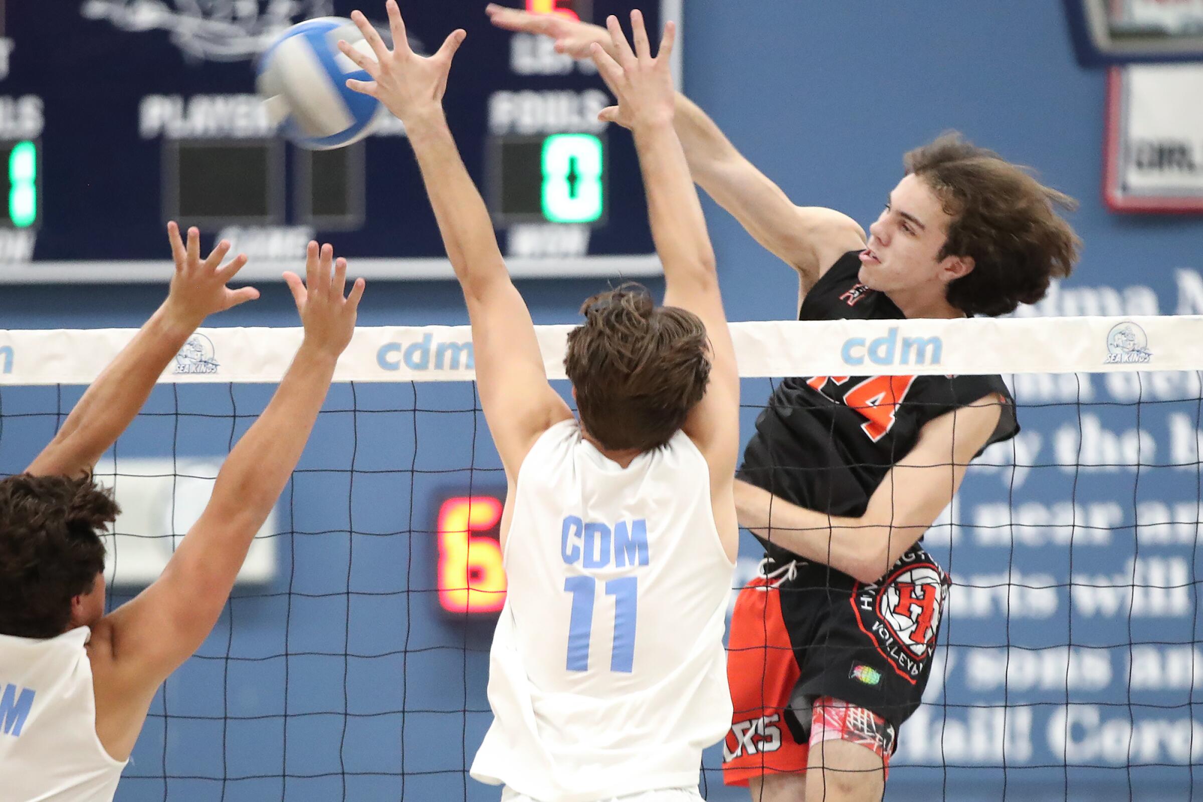 Nick Ganier (24) of Huntington Beach makes a kill past the block of Sterling Foley (11) during Surf League boys' volleyball match on Wednesday.