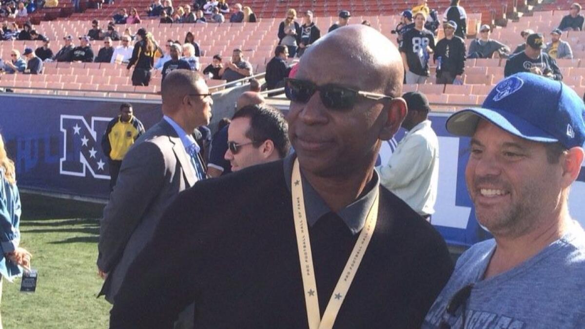 Hall of Fame running back Eric Dickerson poses for a photograph with a fan Sunday on the Rams' sideline before a game against the Cardinals at the Coliseum.