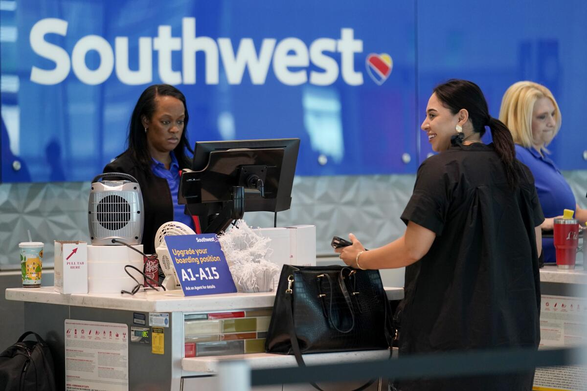 A Southwest Airlines customer service representative, left, assists a traveler.