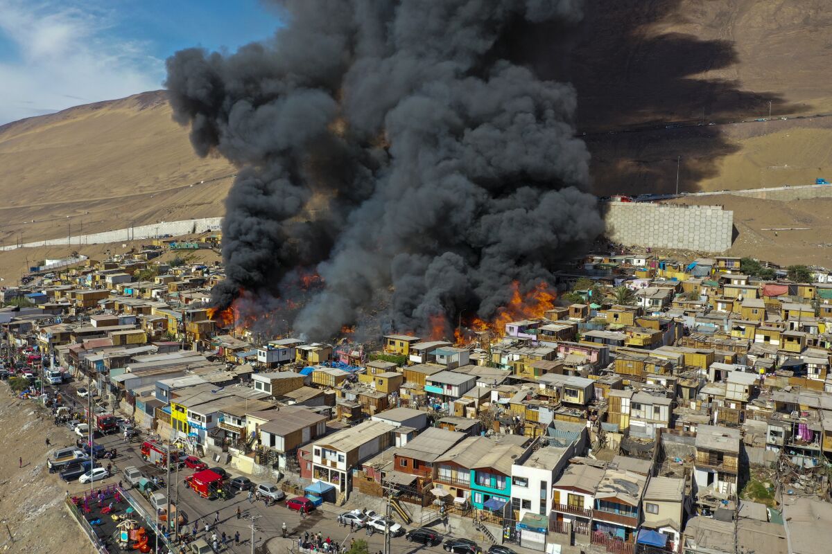 Houses burn during a fire in the low income neighborhood of Laguna Verde, in Iquique, Chile, Monday, Jan. 10, 2022. According to authorities the fire destroyed close to 100 homes of the neighborhood which is populated mostly by migrants. (AP Photo/Ignacio Munoz)