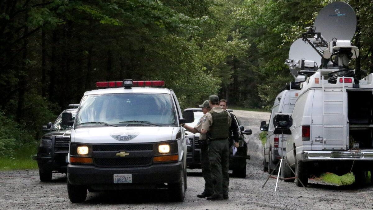 Police from the Washington Department of Fish and Wildlife confer with the King County medical examiner's office on a remote gravel road above Snoqualmie, Wash., following a fatal cougar attack on Saturday.