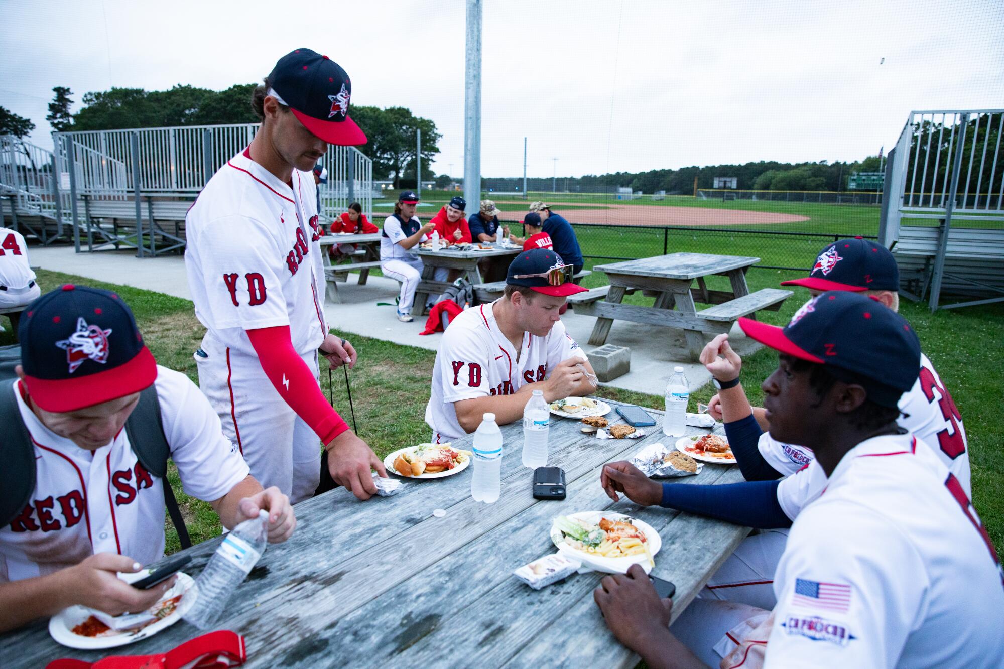 Yarmouth-Dennis Red Sox players have a team dinner on picnic tables after a game against the Orleans Firebirds.