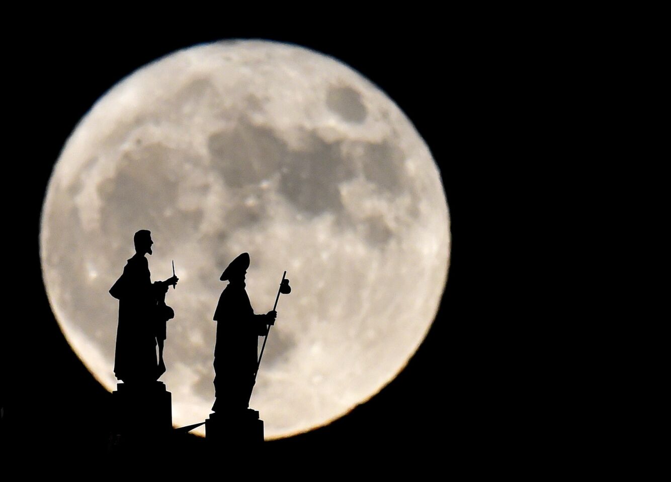 Statues on the Almudena Cathedral are silhouetted against a supermoon in Madrid, Spain.