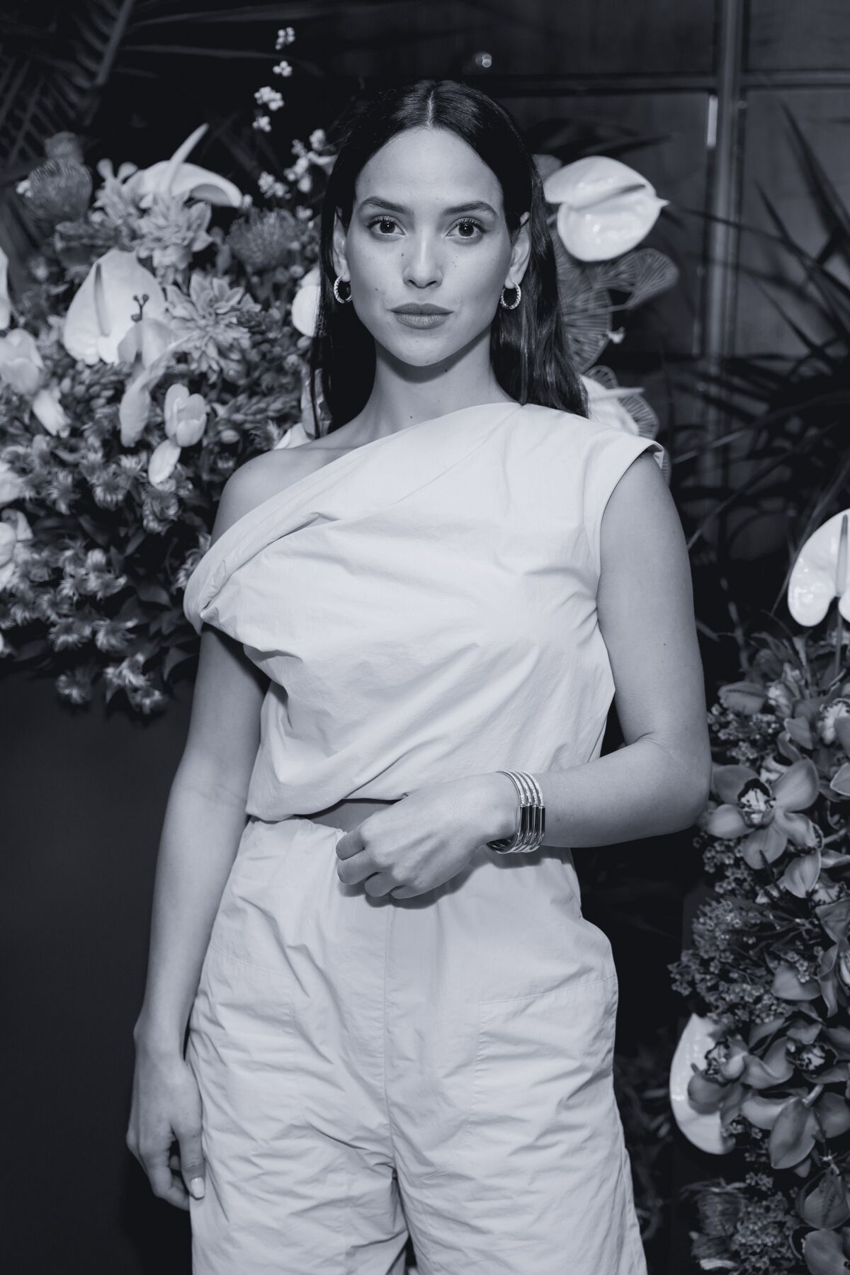 A woman stands in front of a leafy background