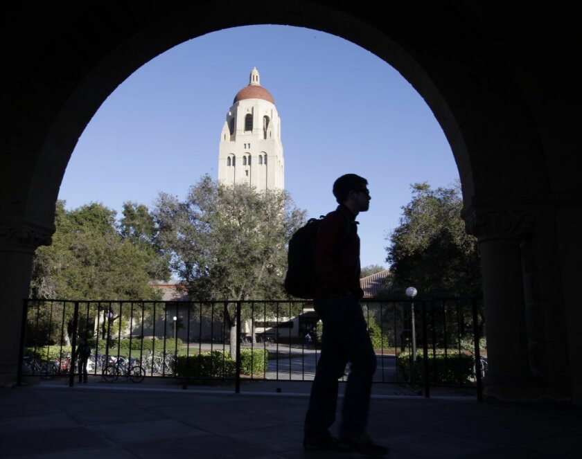 A student walks at Stanford University with Hoover Tower in the background.