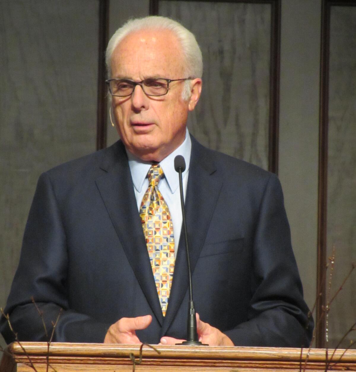 Pastor John MacArthurn stands behind a lectern