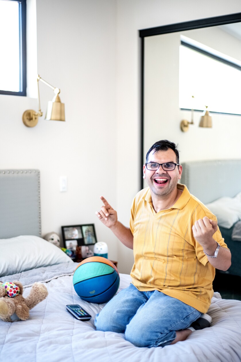 A man kneels on a bed next to a basketball.
