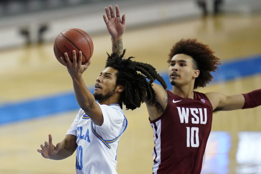 UCLA guard Tyger Campbell, left, shoots against Washington State guard Isaac Bonton, right, during the second half of an NCAA college basketball game Thursday, Jan. 14, 2021, in Los Angeles. (AP Photo/Ashley Landis)