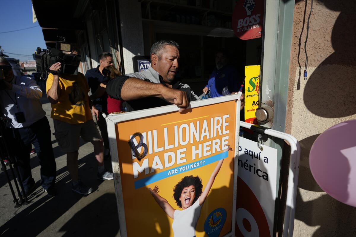 Hector Avalos puts up a sign outside the Las Palmitas Mini Market where the winning Powerball lottery ticket was sold.