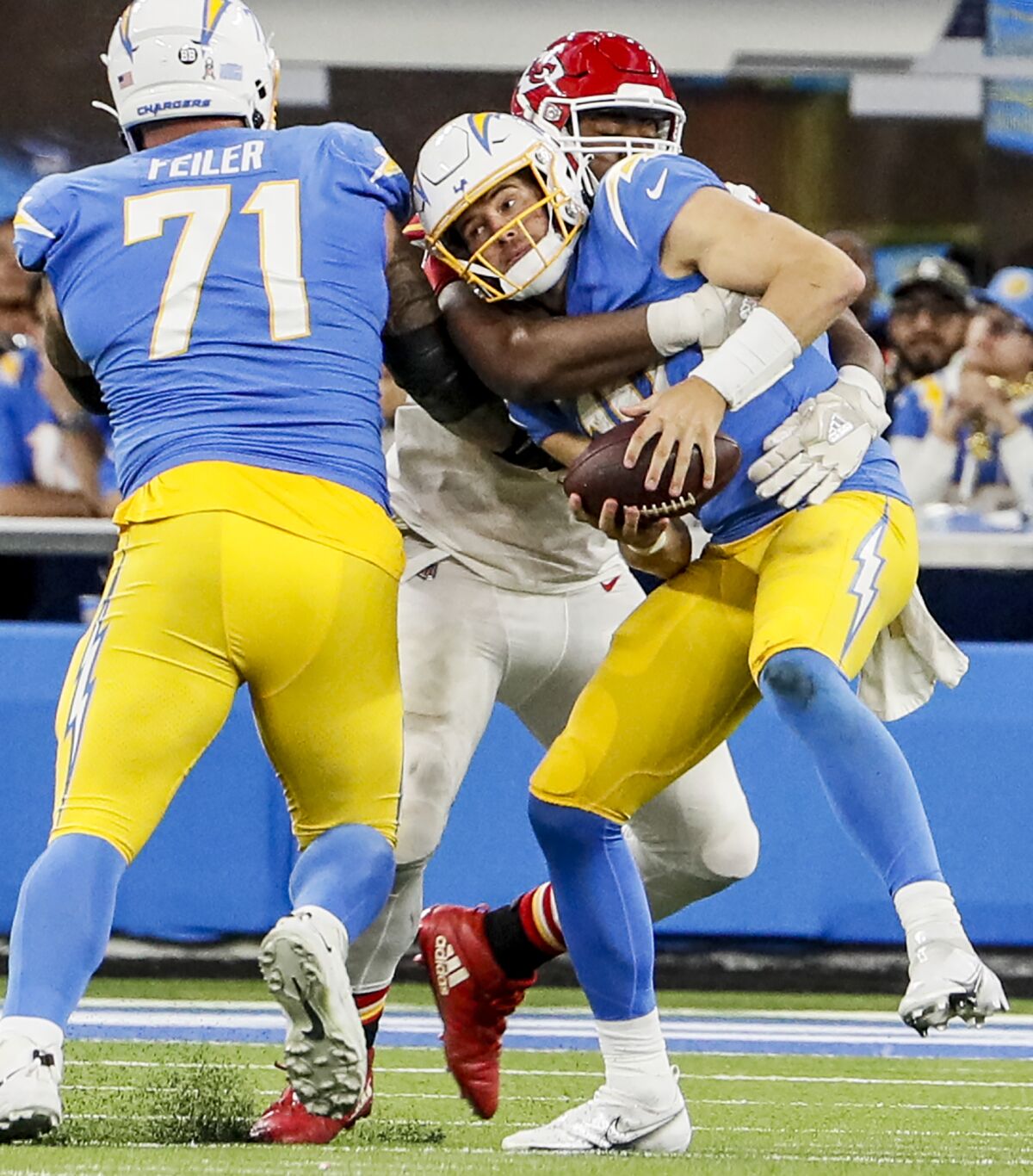 Le quart-arrière des Chargers Justin Herbert (10) est attaqué par le plaqueur défensif des Chiefs Chris Jones (95).