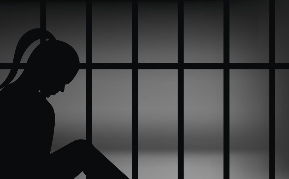A woman silhouetted against prison bars.
