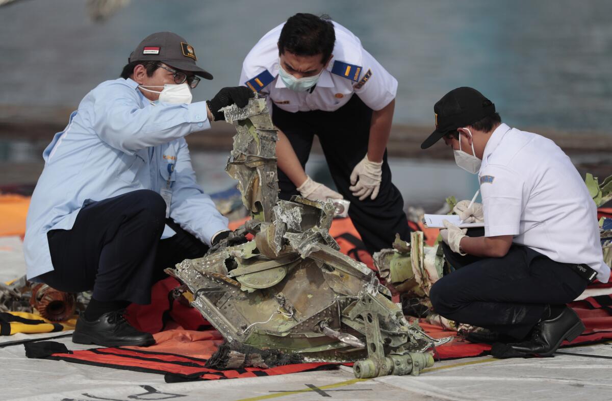 FILE - In this Jan. 21, 2021, file photo, investigators inspect a pieces of the Sriwijaya Air flight SJ-182 retrieved from the Java Sea where the passenger jet crashed on Jan. 9, at Tanjung Priok Port in Jakarta, Indonesia. A lawsuit filed in Seattle against Boeing alleges a malfunctioning autothrottle system on the older 737 jet led to the January crash of the Sriwijaya Air flight that killed all 62 people on board. (AP Photo/Dita Alangkara, File)