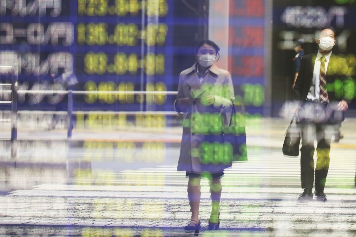 People are reflected on the electronic board of a securities firm in Tokyo, Wednesday, April 6, 2022. Asian stocks followed Wall Street lower Wednesday after a Federal Reserve official's comments fueled expectations of more aggressive interest U.S. rate hikes and the White House announced more sanctions on Russia. (AP Photo/Koji Sasahara)
