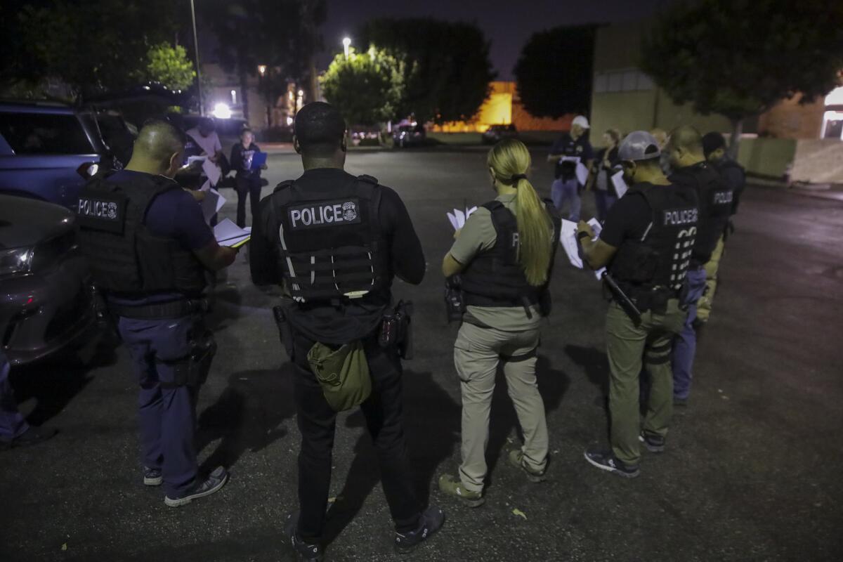 Immigration and Customs Enforcement agents huddle in a parking lot before raiding.