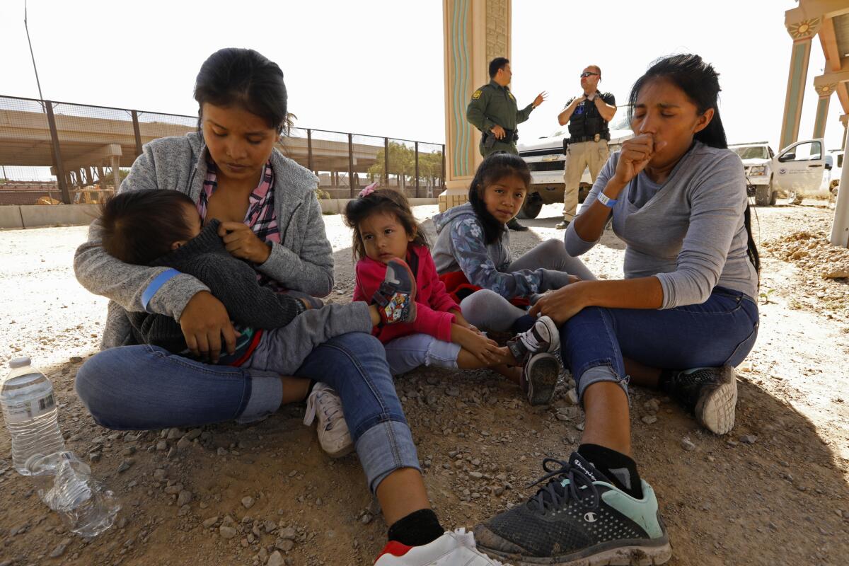 Women and children who just crossed the U.S.-Mexico border illegally in El Paso wait to be transported to a detention facility.