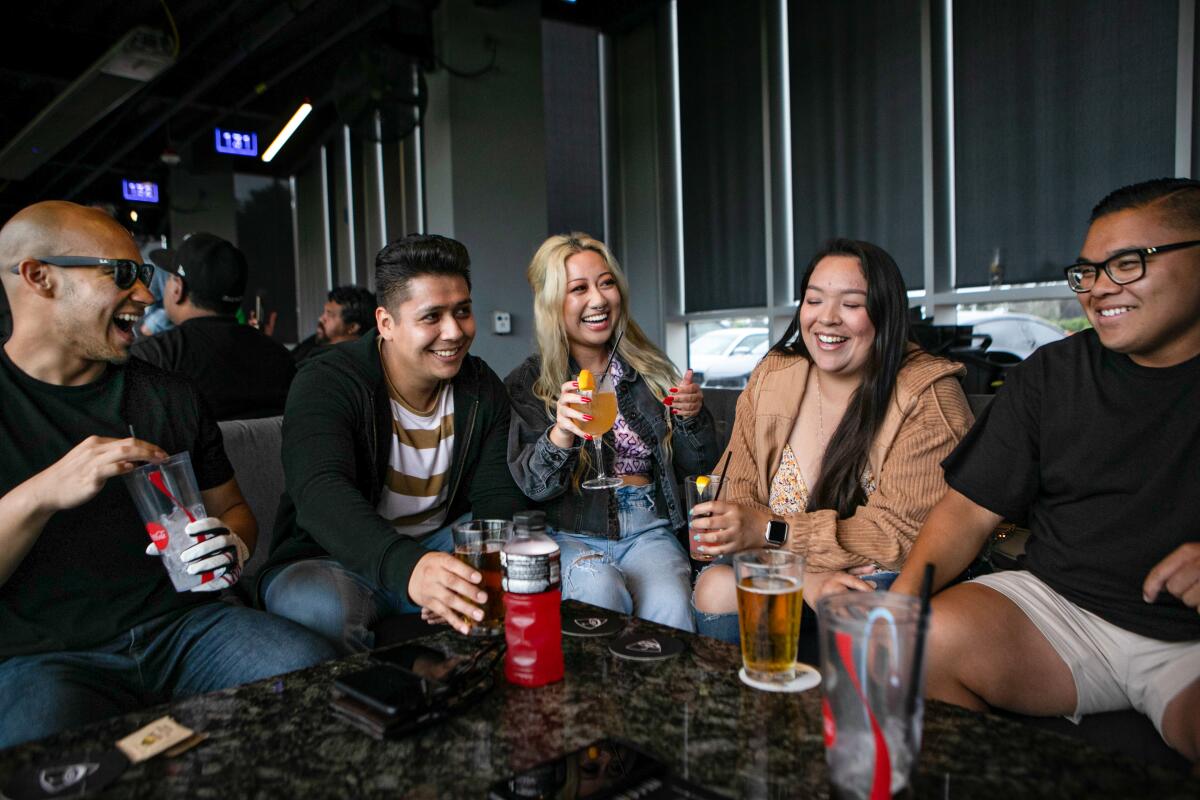 Friends sit around a low table enjoying drinks and laughing.