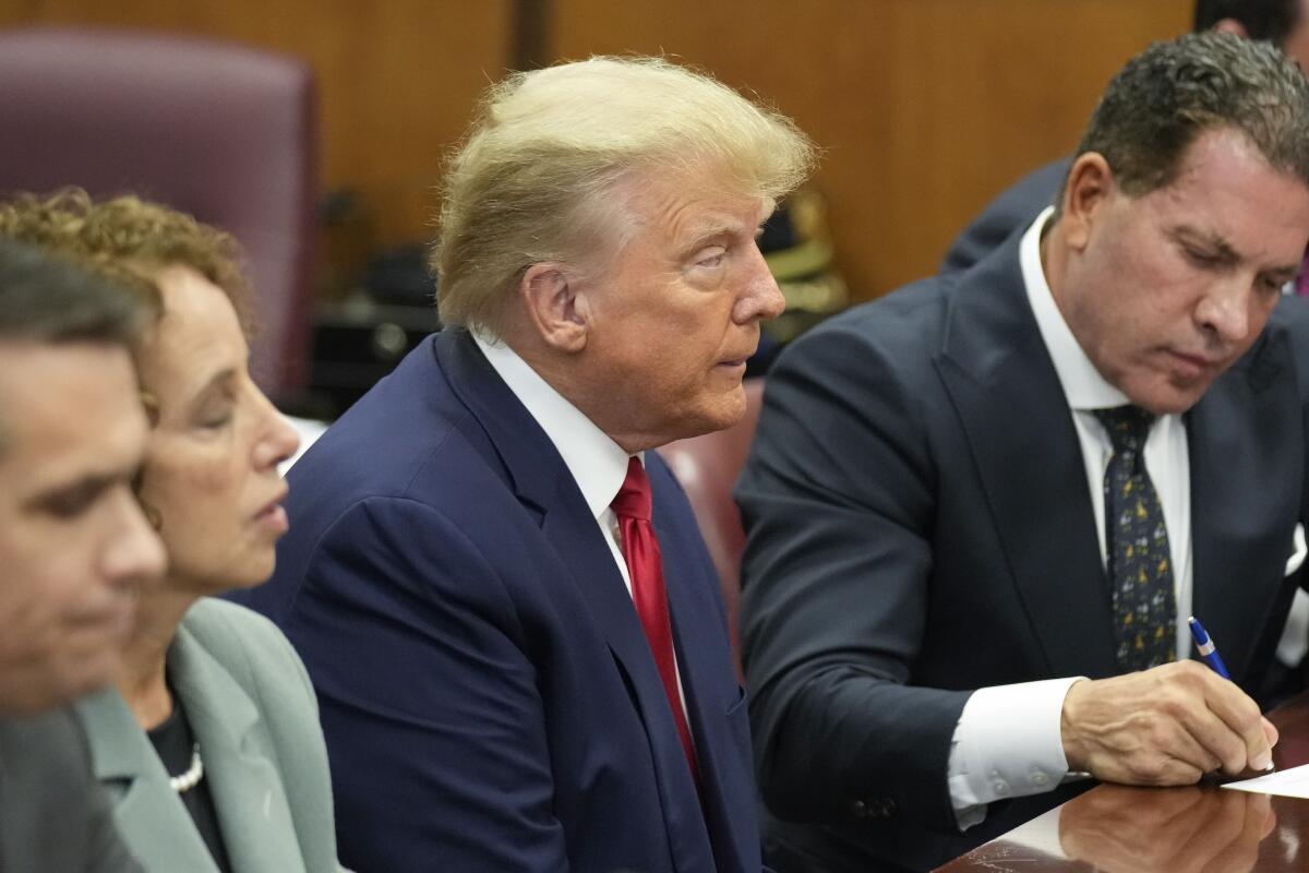 Donald Trump appearing in court at a table between other people