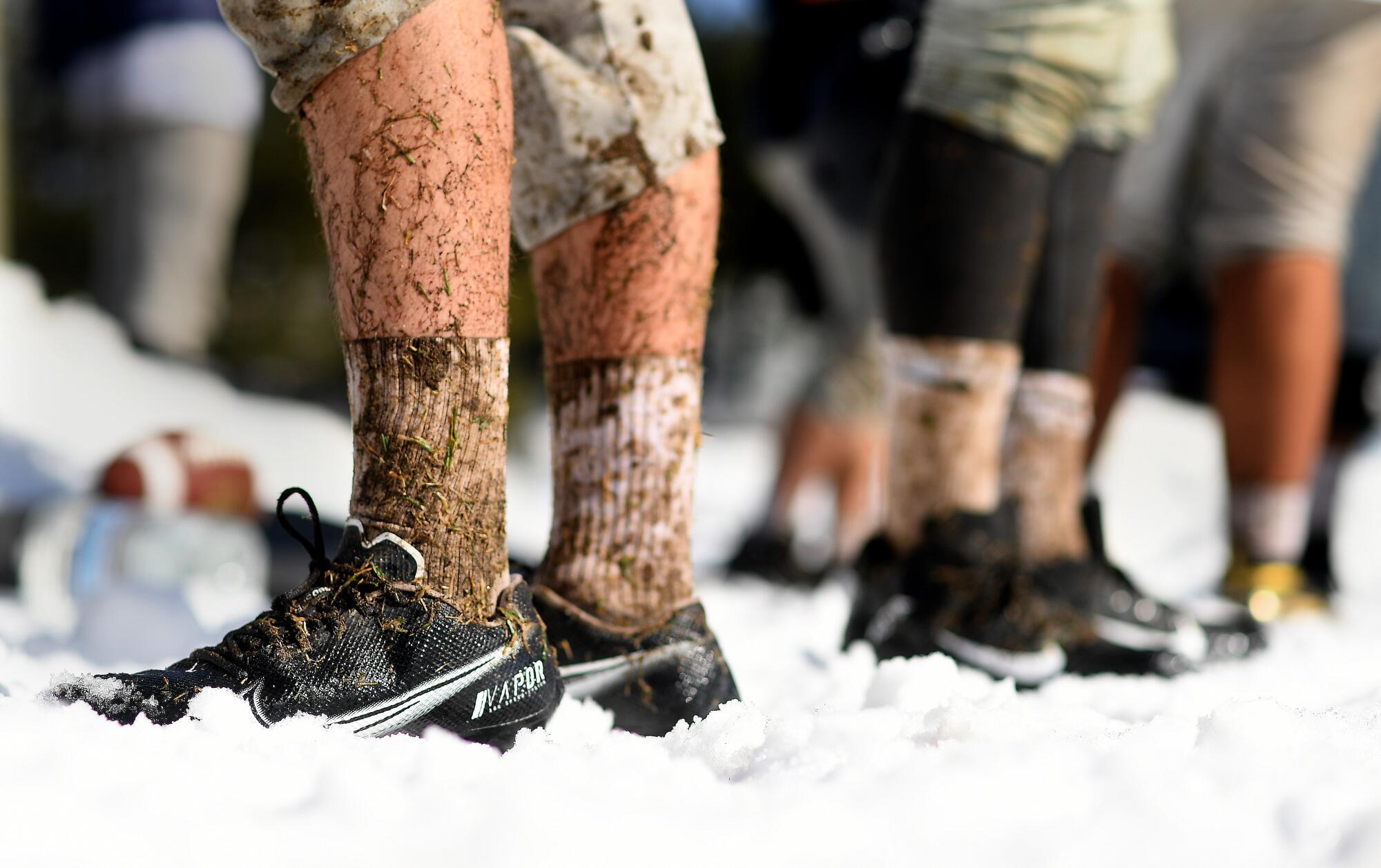 Rim of the World High School football players practice on a muddy field from melting snow in Rimforest on Tuesday.