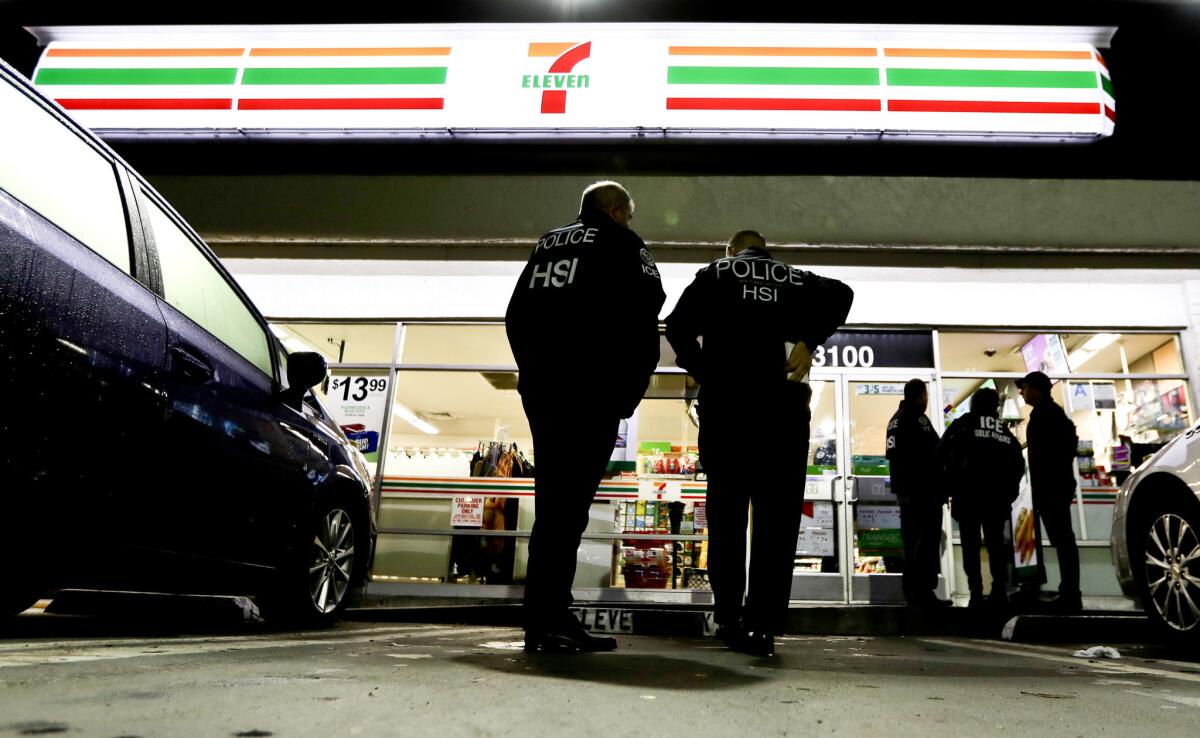 Immigration agents serve an employment audit notice at a 7-Eleven store in Los Angeles on Jan. 10, 2018..