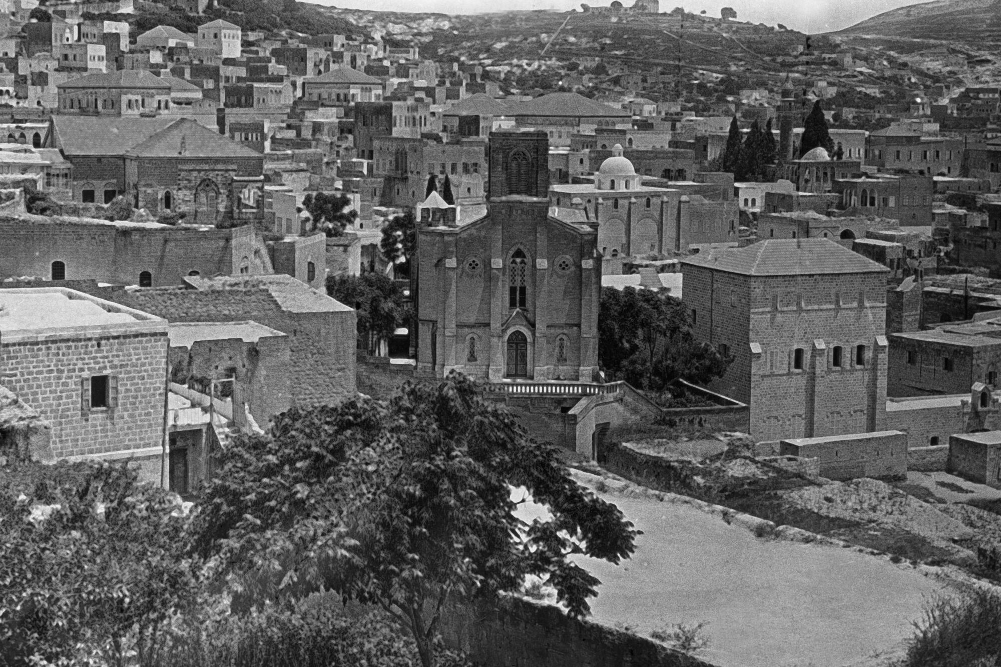 A black-and-white photo of an old city amongst some hills