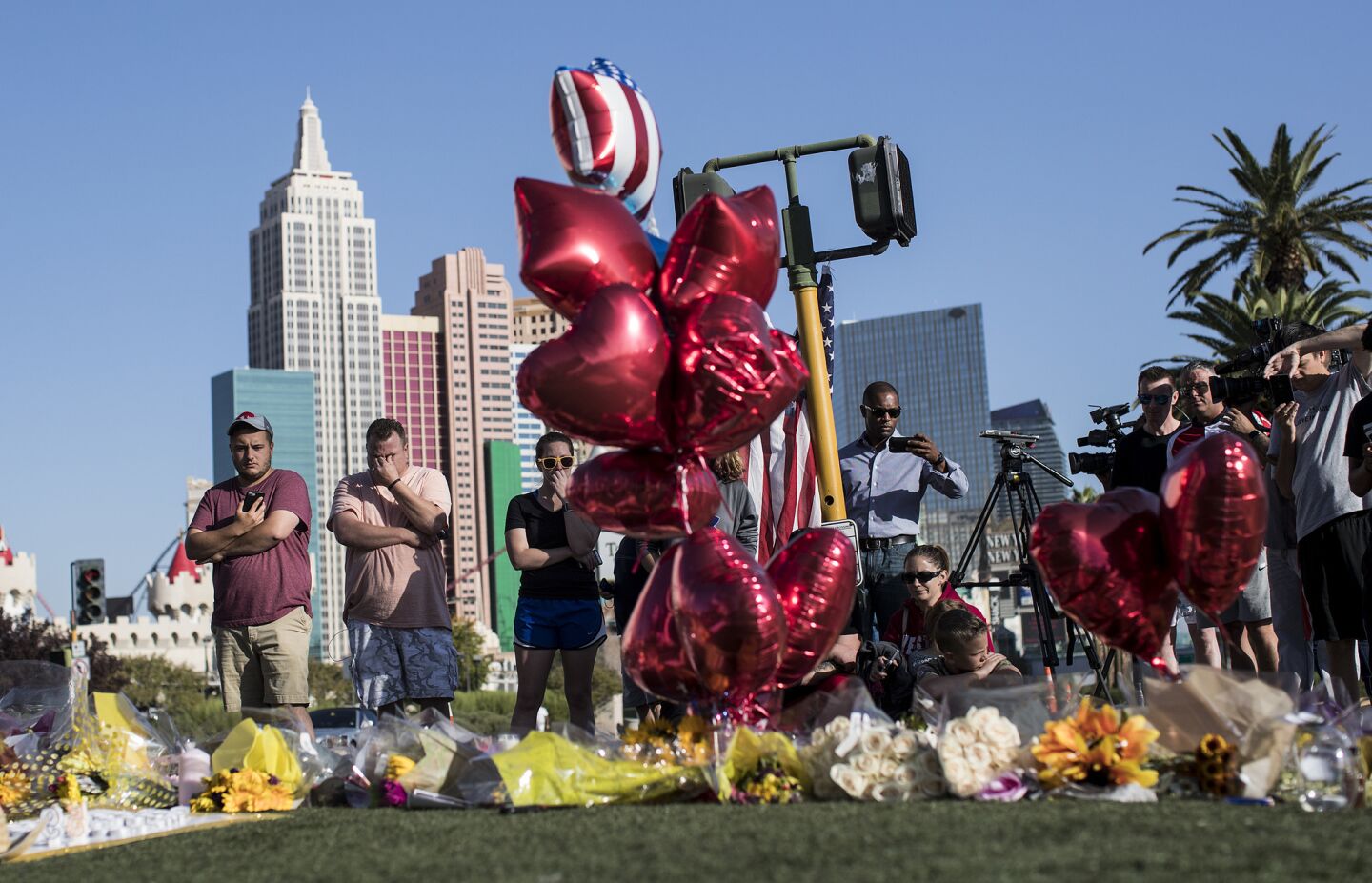 People stop to pay their respects at a memorial for the victims of the mass shooting on the median off Las Vegas Boulevard near the crime scene.