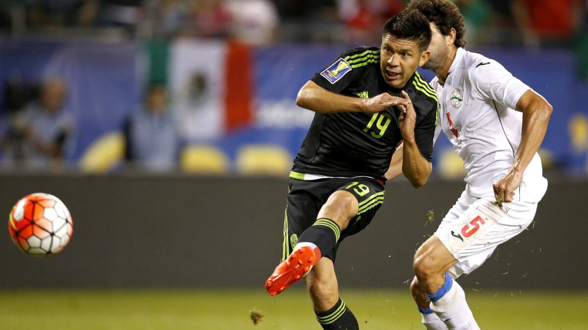 Mexico forward Oribe Peralta scores in front of Cuba defender Jorge Luis Clavelo in the first half of a Gold Cup game on Thursday night in Chicago.