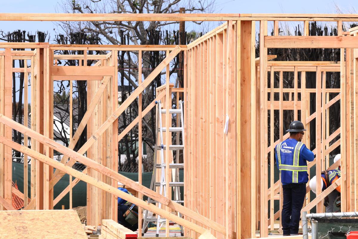 A worker is surrounded by the frame of the first home to be rebuilt in the fire zone last month in Pacific Palisades.