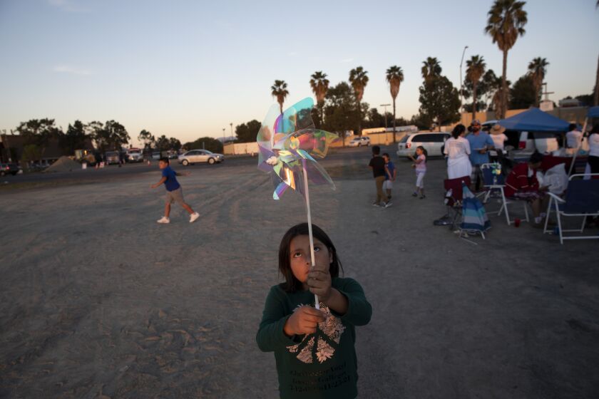 Zyxxie Gaspar, 9, plays with a pinwheel during a celebrate for what would have been her cousin's Angel Domingo Gaspar Gallegos' 13th birthday on Saturday, Feb. 12, 2022 in San Diego, California. The celebration began in an empty lot near Jamacha Road and Cardiff Street and continued with a walk around the neighborhood in memory of Gallegos. Gallegos was killed by a stray bullet on Thanksgiving night while playing outside of his family's home. The family is still searching for answers as to what happened that night.