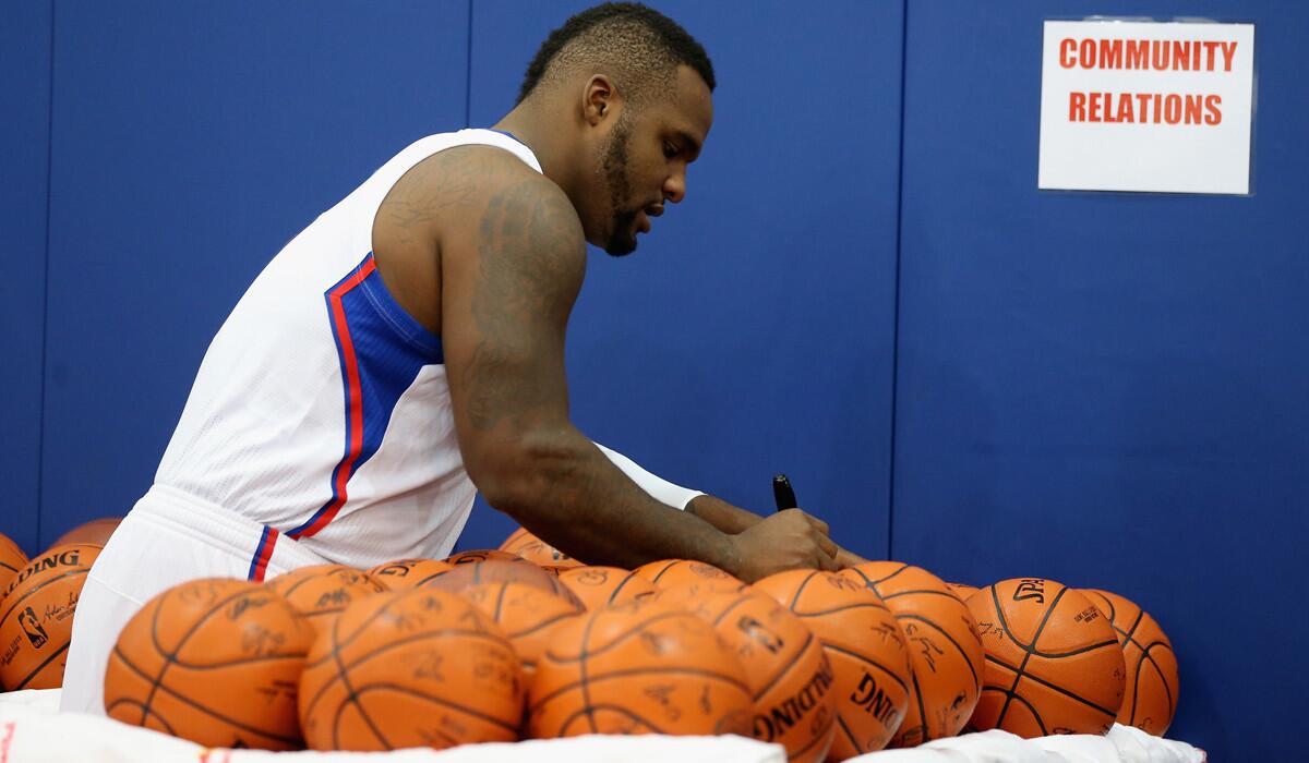 Clippers power forward Glen Davis autographs basketballs during media day last week.