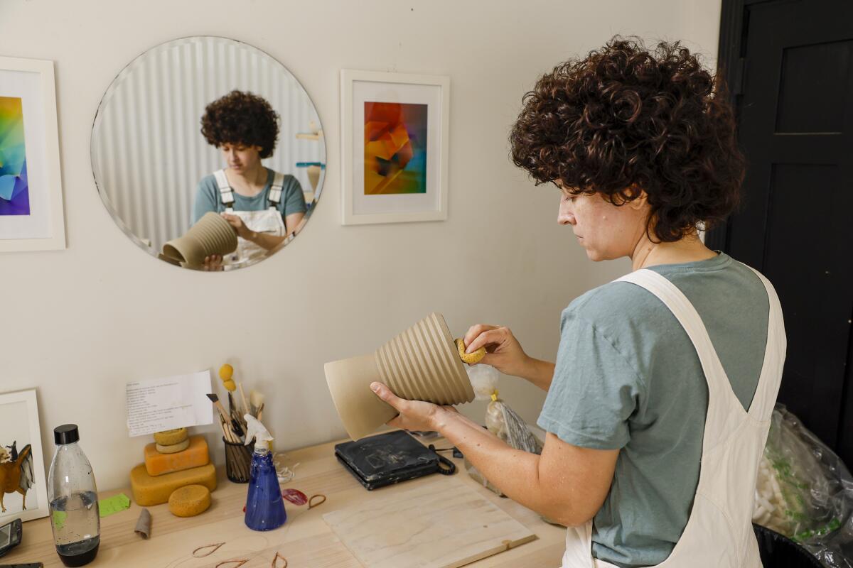 Potter Becki Chernoff sands a vase.