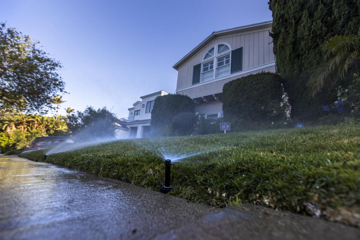  Sprinklers water grass at a house.