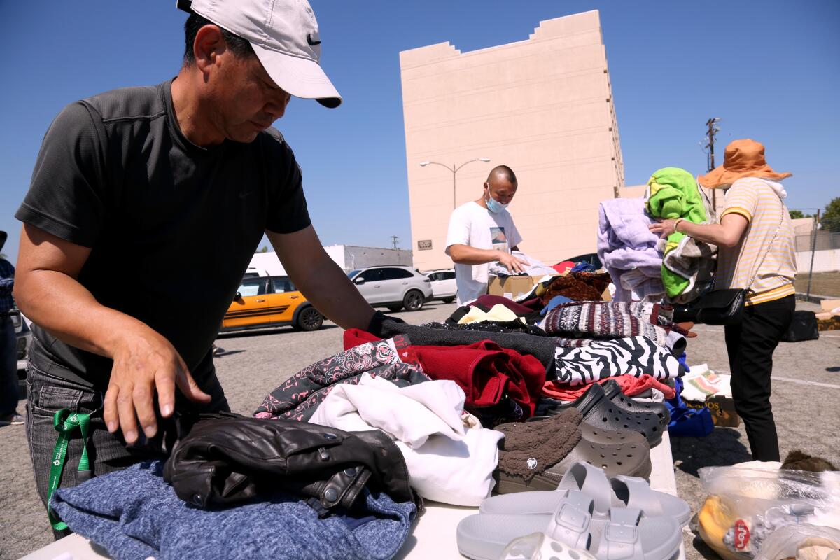 A man organizes clothing on a table set up in a parking lot.