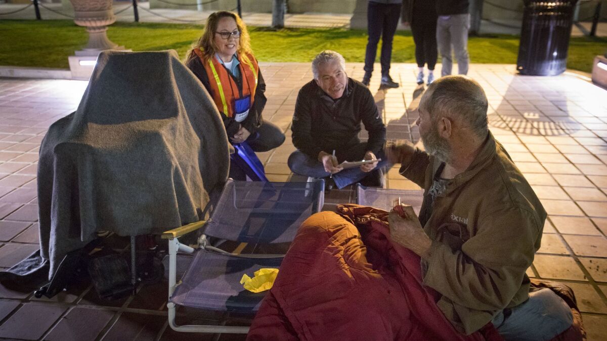 Jill Kernes, left, and Bill Geppert, center, conduct a survey with John Ross, right, who had been sleeping near the fountain in Horton Plaza, during the annual point-in-time homeless count before dawn on Friday.