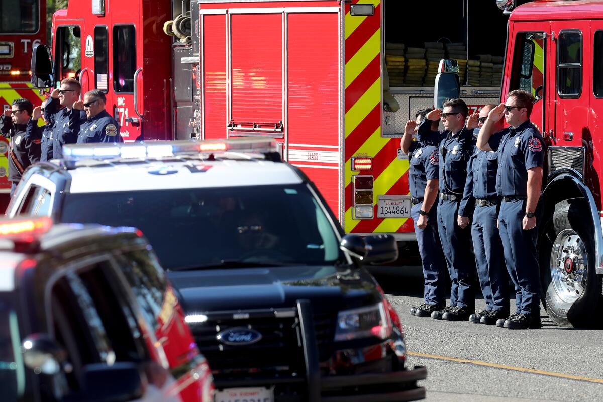 Members of the Costa Mesa, far right, and Santa Ana, far left, fire departments stand at attention Tuesday.