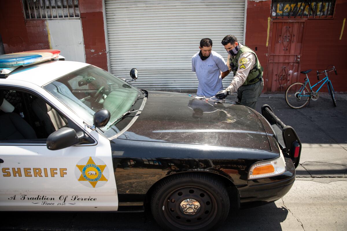 A sheriff's deputy with a man in handcuffs