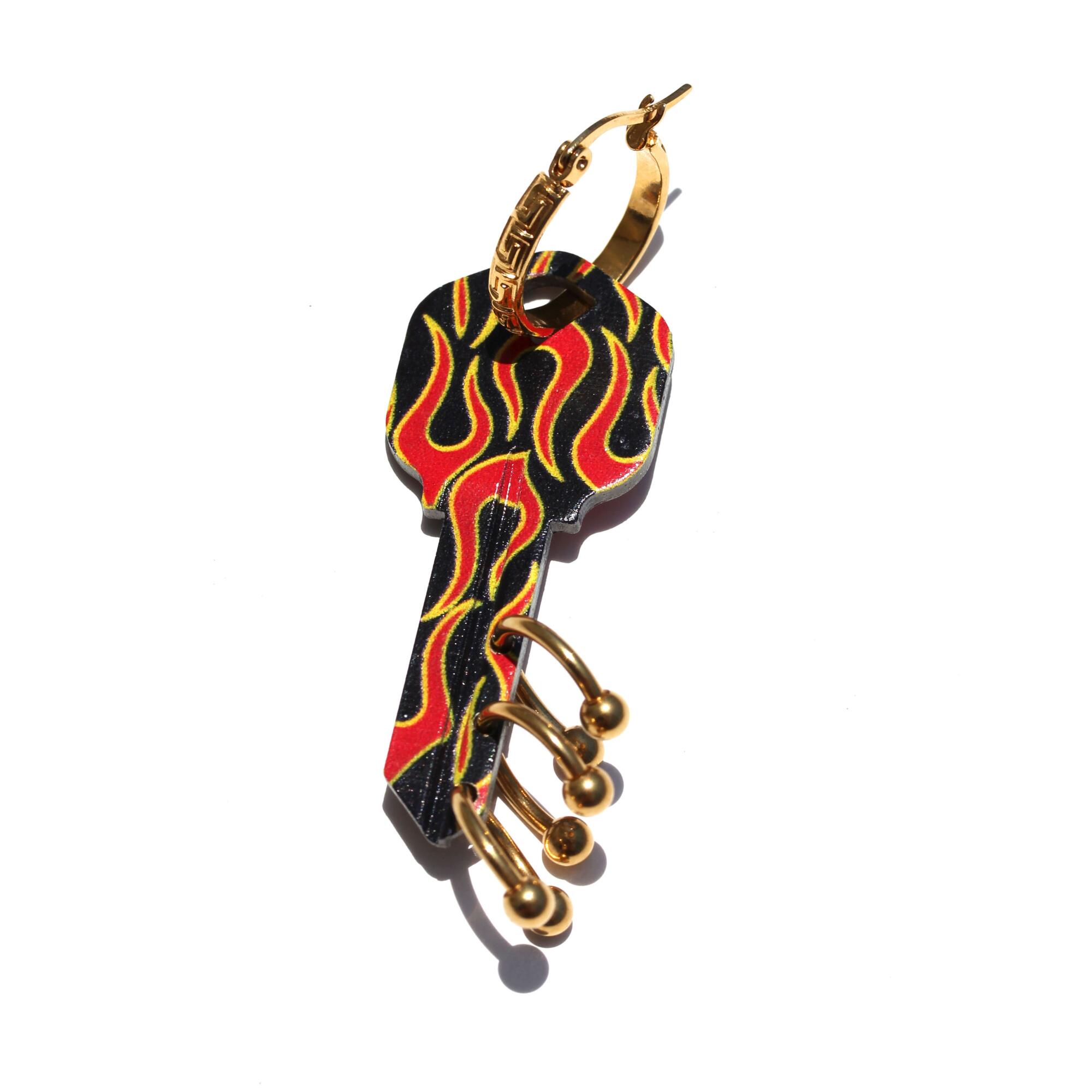 An earring shaped like a house key and painted with racing flames.