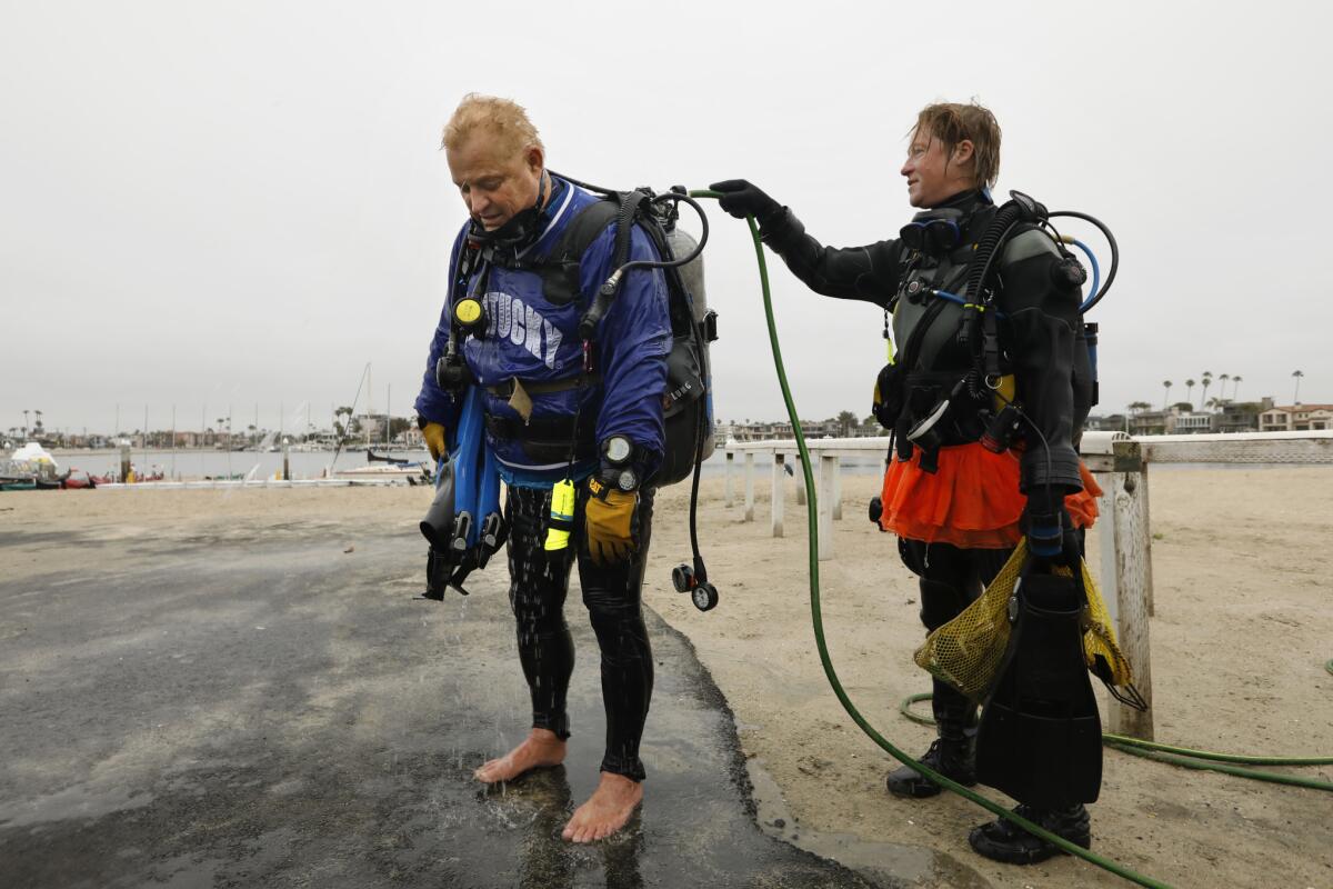 Ashley Arnold rinses Rog Hanson off with a hose after a dive Alamitos Bay. Rog Hanson, 68, left, teamed up with dive instructor Ashley Arnold two years ago to keep watch over a small colony of Pacific seahorses. (Carolyn Cole/Los Angeles Times)